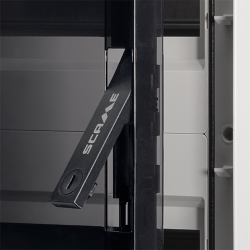 Centralita industrial estanca Scame para instalación en pared. Detalle de la manija de cierre con puerta ahumada transparente y estructura interna, diseñada para proteger los componentes eléctricos en entornos industriales y exteriores gracias a su alta resistencia a los agentes atmosféricos.
